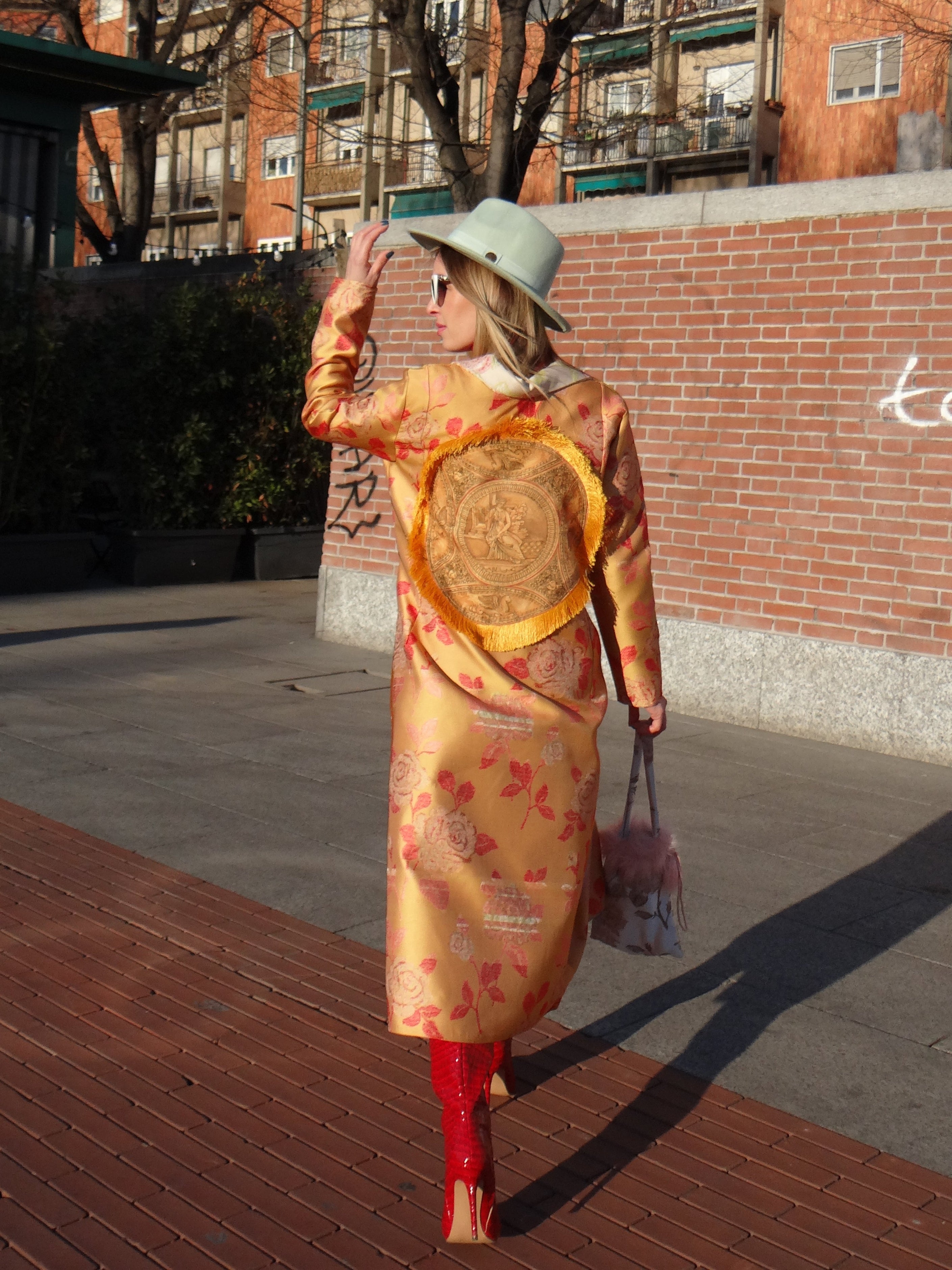 Back view of handmade orange jacquard coat showing decorative fringed panel